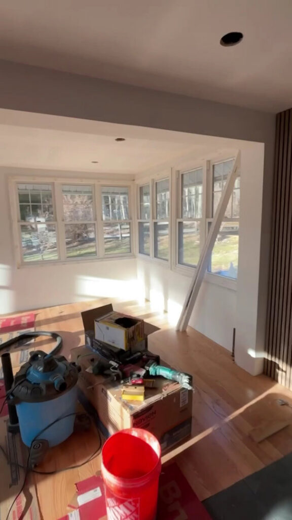 A room undergoing renovation with new windows and construction tools by Golden Tile Construction in Yonkers, NY.