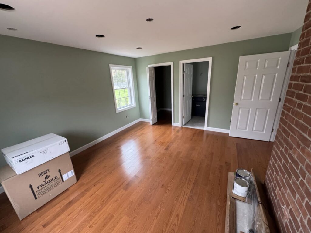 An interior room undergoing renovation, showing new paint, hardwood floors, and fixture boxes by Mainville Construction & Remodeling LLC in Newington, CT.