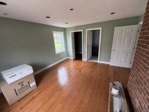An interior room undergoing renovation, showing new paint, hardwood floors, and fixture boxes by Mainville Construction & Remodeling LLC in Newington, CT.