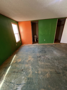 A room undergoing renovation with the subfloor exposed and a view into a small bathroom, handled by Cosa Cleanouts & Junk Removal in Topeka, KS.