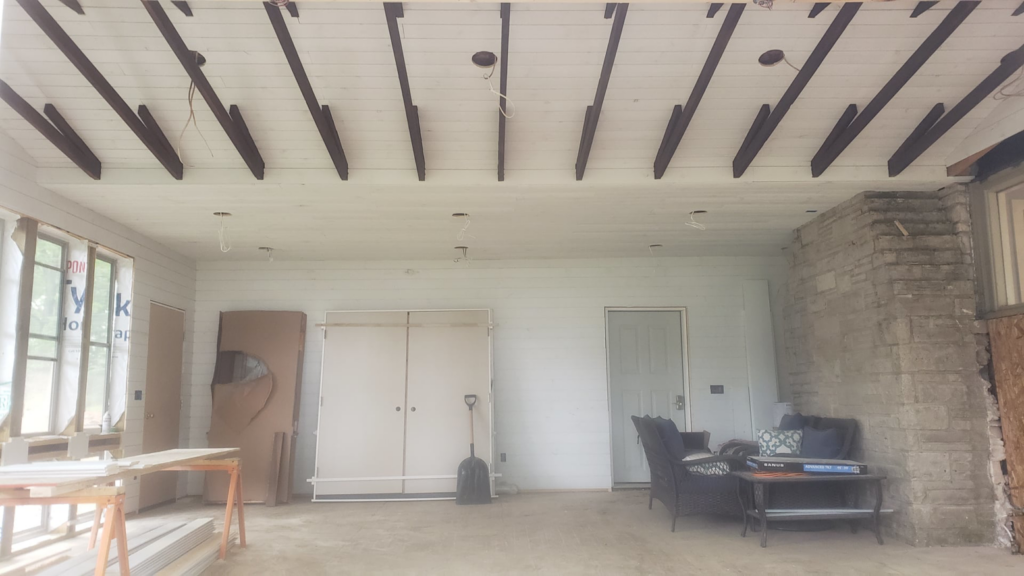 A room undergoing renovation with new ceiling panels, exposed wiring for lights, and unfinished walls by Ironside Home Improvements, LLC in Madison, WI.