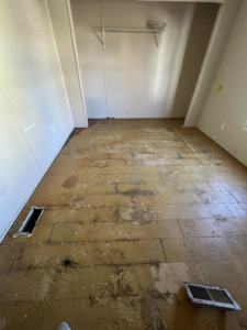 A room with yellowish subfloor exposed and a closet area, prepared for new flooring installation by Cosa Cleanouts & Junk Removal in Topeka, KS.