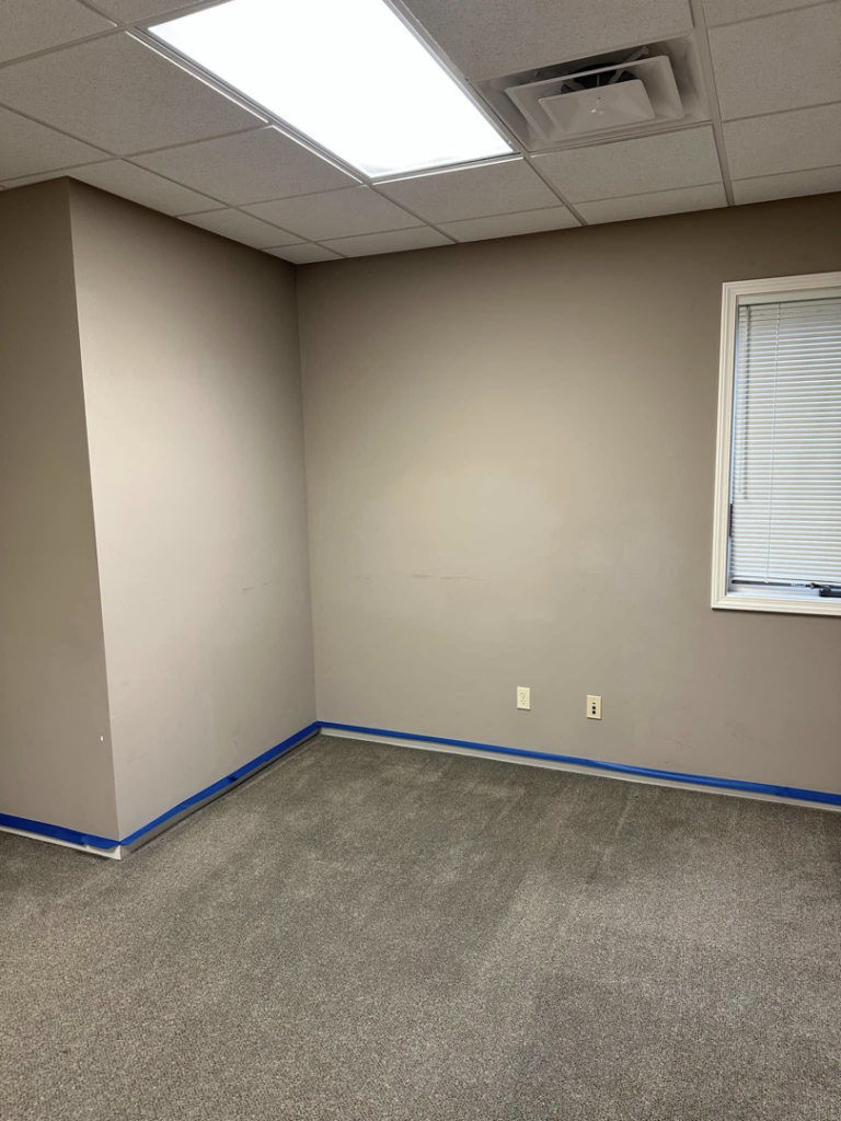 A room with blue painter's tape applied to the baseboards, prepared for a professional painting job by One Seven Painting LLC in Columbia, MO.