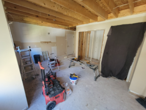 A room under construction with exposed ceiling joists, new framing, and renovation tools by Raleigh Renovations & Flooring in Cary, NC.