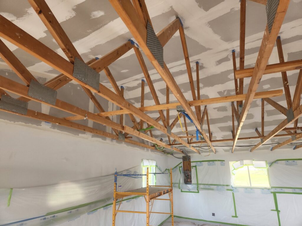 A room under construction showing exposed ceiling trusses and new drywall installation by Branham Handyman in Salt Lake City, UT