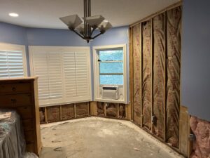 A room undergoing major renovation with walls stripped to studs and insulation by Rockin & Rollin Handyman Services in North Ogden, UT.