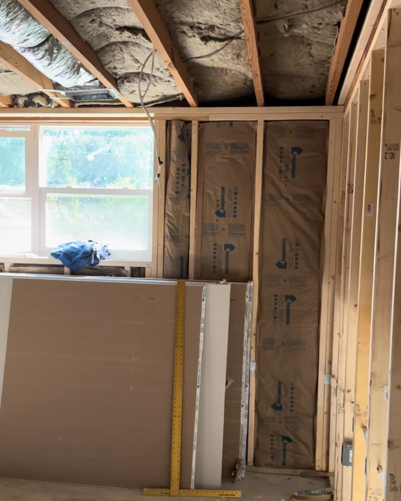 A room under renovation with exposed studs, insulation, and drywall sheets, showcasing work by Under The Wire Renovations in Atlanta, GA.