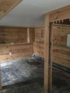 A room under renovation with wood paneling and exposed framing, showcasing handyman services by Lemelin General Contracting in Fall River, MA.