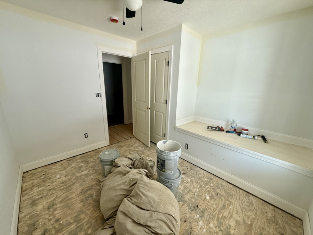 A room undergoing renovation with exposed subfloor, paint buckets, and tools, demonstrating work by Phillips Homes, LLC in Elizabethtown, KY.