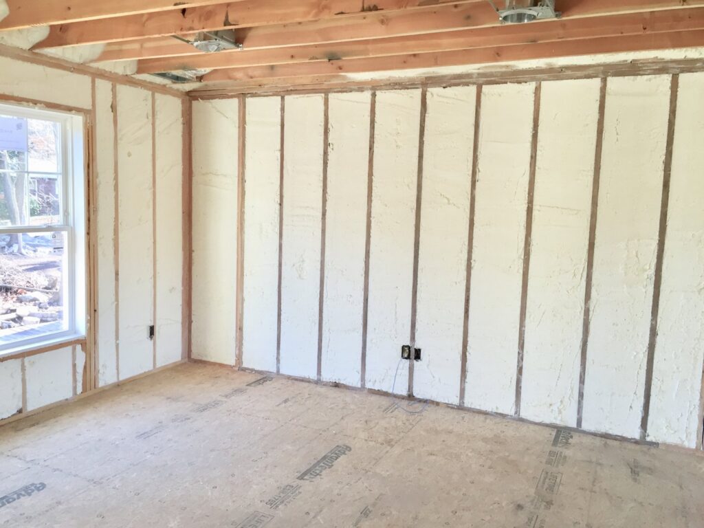 An unfinished room showing spray foam insulation applied between wall studs by Spray Foam Art-Insulation in Stamford, CT.