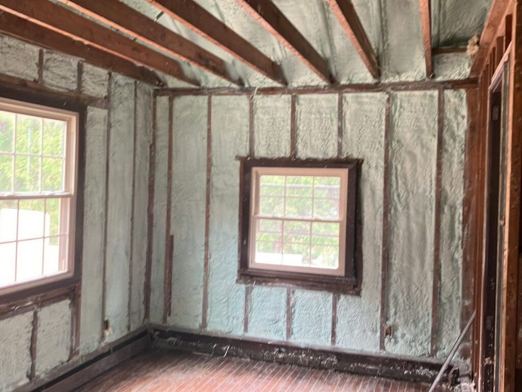 A room with spray foam insulation applied to the walls between studs, showing windows, completed by Metro Insulation in Rockford, IL.
