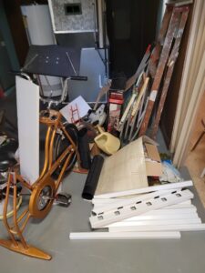 A room cluttered with a bicycle, ladders, and boxes, showing a space ready for junk removal by KJ Haul Away Junk Removal in Cedar Rapids, IA.