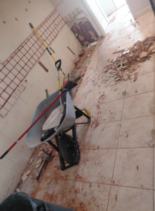 A room with demolition debris on the floor, a wheelbarrow, and tools, showing a clean-up job by Arizona Junk Removal LLC in Phoenix, AZ