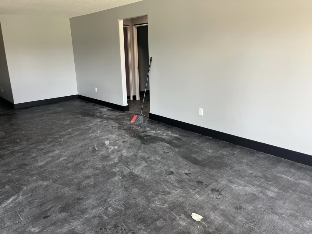 A room undergoing renovation with freshly painted grey walls and new flooring being installed by Drew's Home Repair and Handyman Service in Wichita, KS.