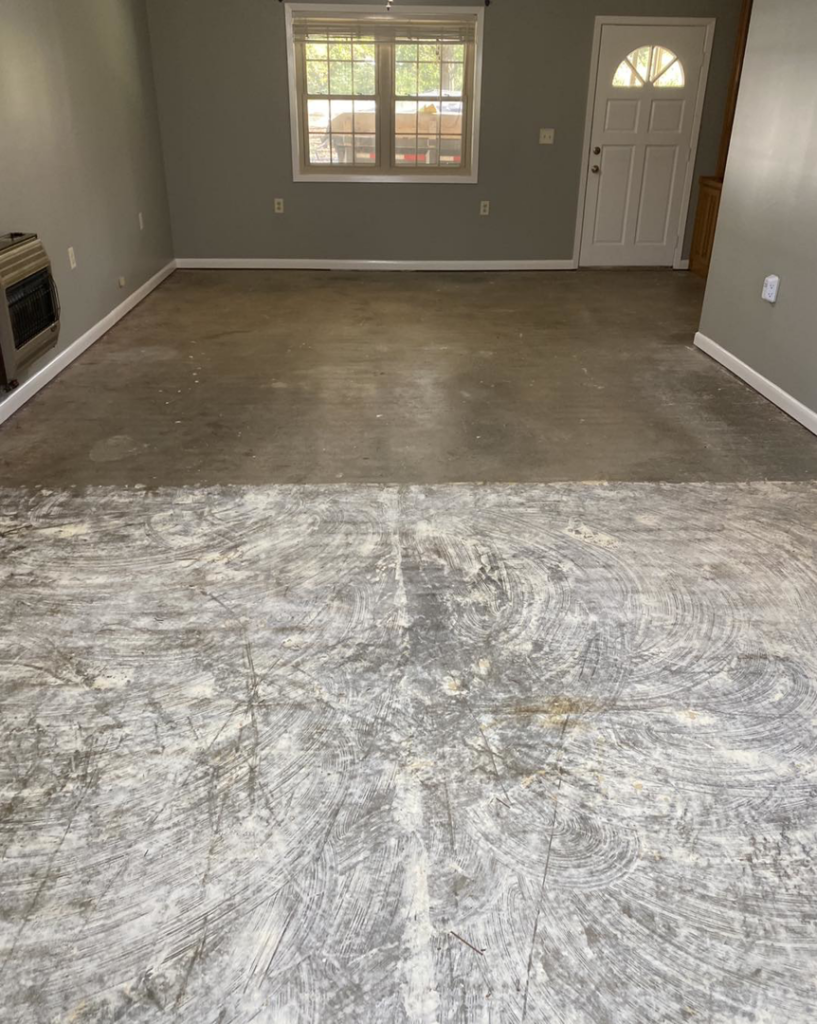 An empty room with a concrete floor showing adhesive residue, prepared for new flooring installation by Tupelo Handyman in Tupelo, MS.
