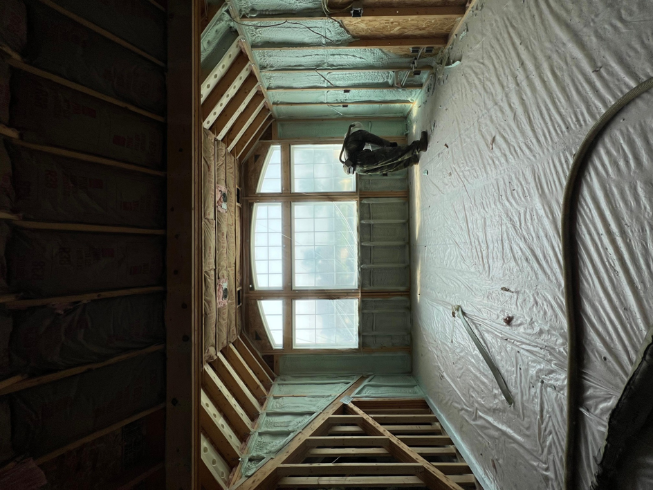 A newly insulated room with spray foam on walls and ceiling, featuring a large window, by Insulation Man in Chesterfield, MI.
