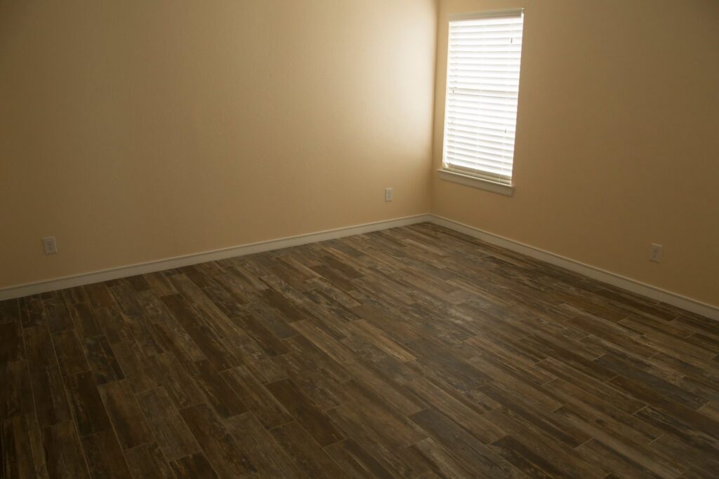 A newly renovated room featuring stylish wood-look tile flooring and freshly painted walls, completed by Custer Remodeling in Plano, TX.