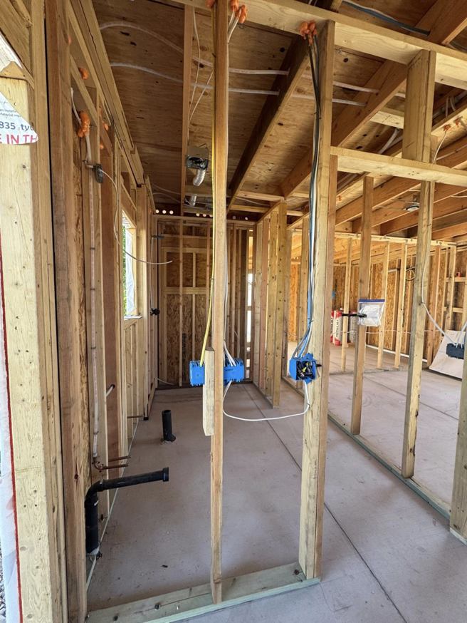 Exposed wooden framing with rough-in electrical wiring and plumbing during construction by CK Customs LLC in Surprise, AZ.