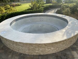 A newly constructed round spa featuring decorative stone veneer and coping, ready for use by JJB Pools & Spas in Tampa, FL.