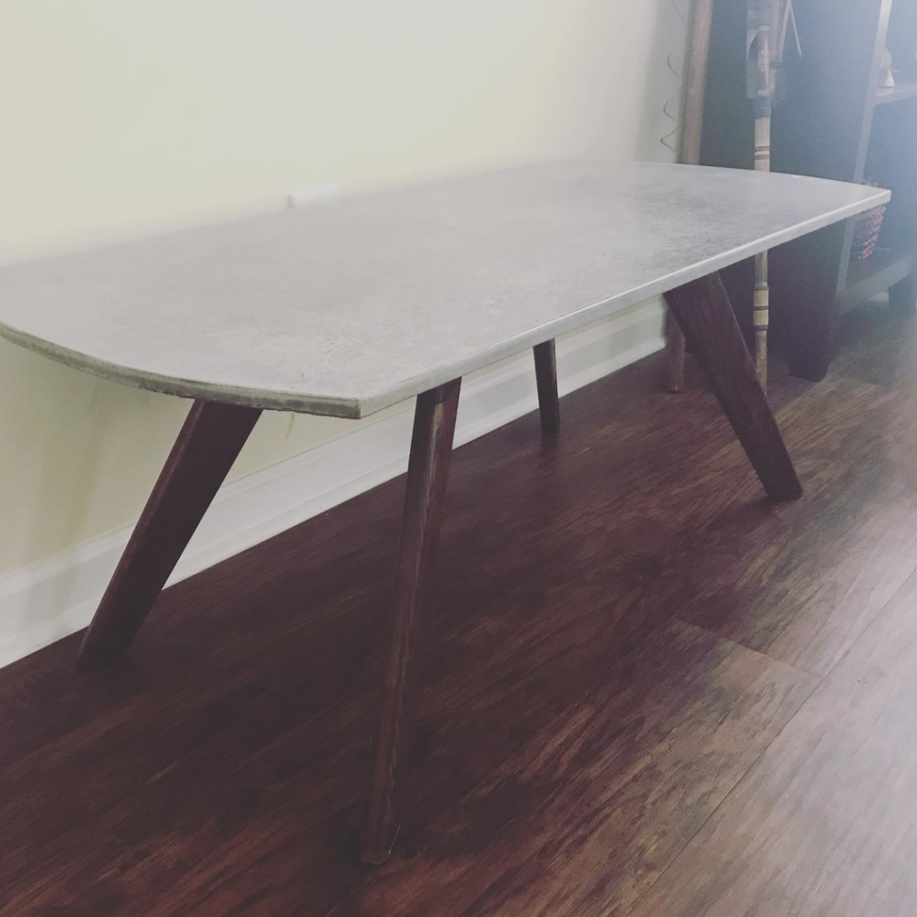 A custom-built rounded-end table with dark wooden legs by VanArt Designs in Nashville, TN