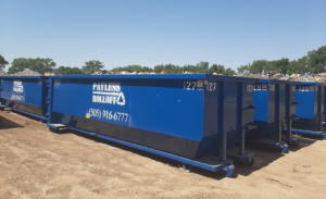 A row of blue roll-off dumpsters from Payless Rolloff ready for service in Albuquerque, NM.