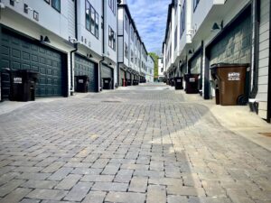 A row of brown trash bins from J.E. McMurtry Disposal & Recycling in front of residential garages in Nashville, TN.