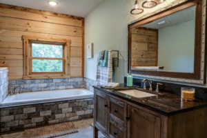 A rustic bathroom renovation with wood paneling, a built-in tub, and a dark wood vanity by GCU Custom Builders in Louisville, KY.