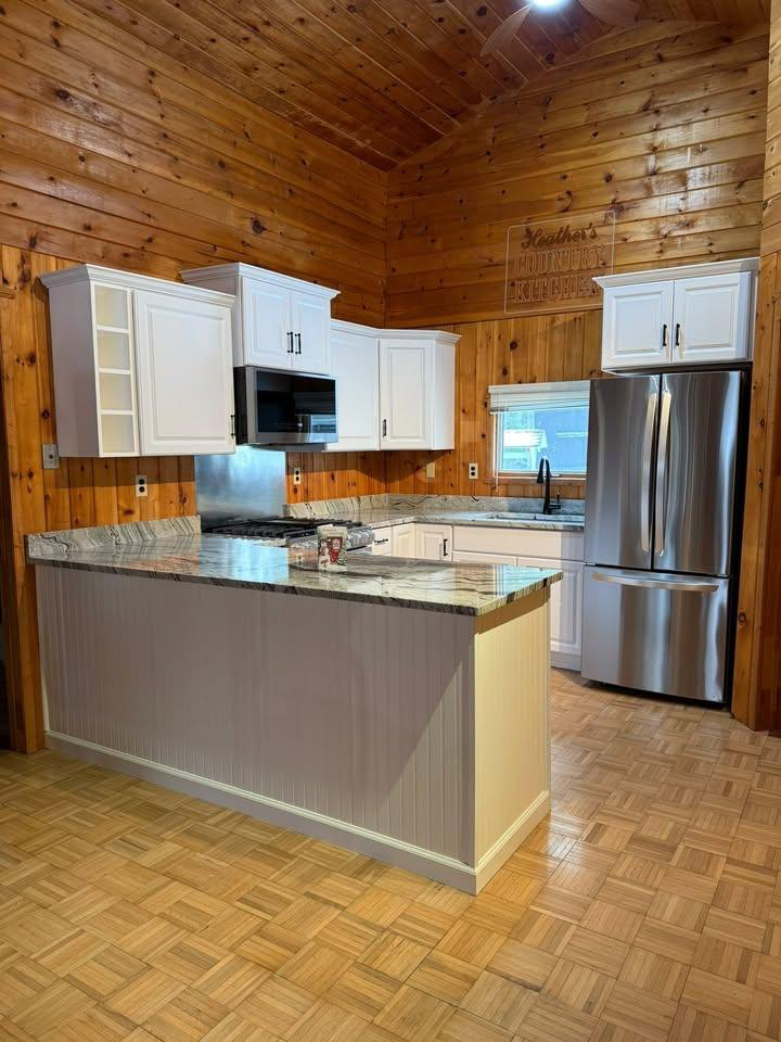 A rustic modern kitchen remodel featuring wood paneling and white cabinets by The Finish Group in Bangor, ME.