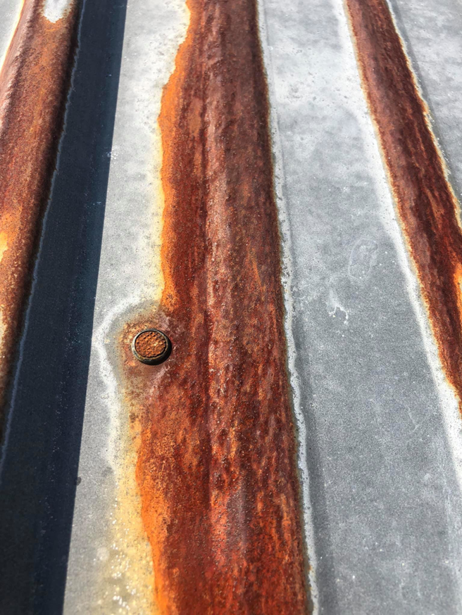 A close-up of a rusty corrugated metal roof in need of repair from Extreme Precision Painting in Elizabethtown, KY.