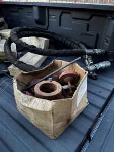 Rusty metal parts and a coiled hose in a truck bed for junk removal by Tracer Transport LLC in Fort Wayne, IN.
