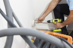 A SafeVent Dryer Vent Cleaning technician works on an exterior dryer vent cover on a home in Wilmington, NC.