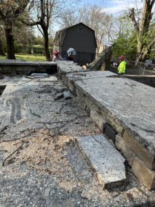 Sawdust and small branches on a stone wall after tree work, showing the cleanup process by Gray's Tree and Crane Service in Evansville, IN.