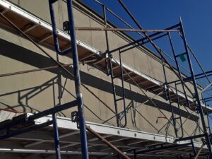 Scaffolding erected against a building exterior wall during a construction project by Modern Wall Systems in Virginia Beach, VA.