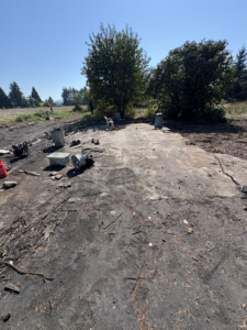 Scattered junk including metal rims, buckets, and branches on a concrete slab for removal by HB Junk Hauling LLC in Springfield, OR.