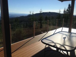 A scenic outdoor deck with glass railings and a table, installed by Myers & Myers Construction in Spokane, WA.