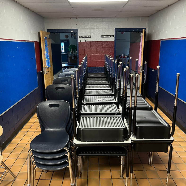 A school hallway with neatly stacked chairs and desks, arranged by Jez Enterprises in Aurora, CO.