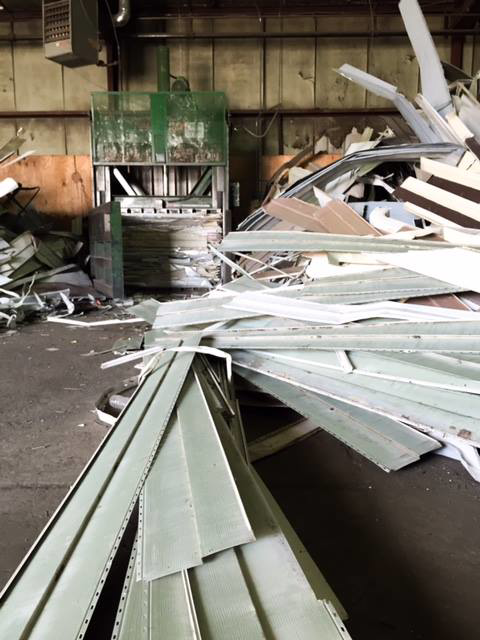Piles of scrap metal siding and a baler for processing materials at Get Green Recycling Co. in Aurora, IL.