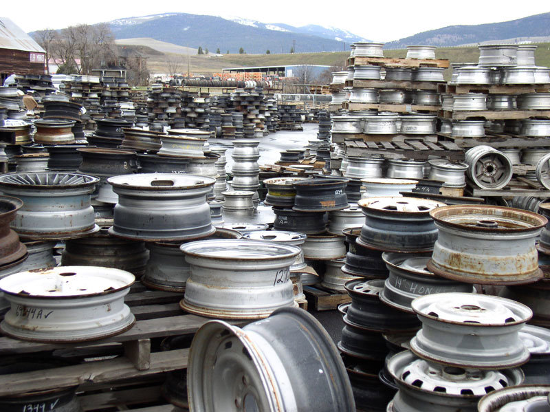 A large yard filled with stacks of scrap metal wheel rims, handled by Cash For Scrap Vehicles / Junk Removal in Minneapolis, MN.