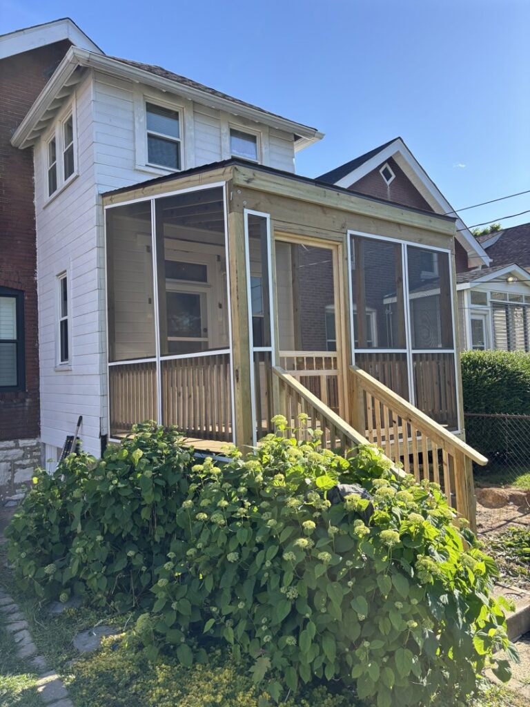 A newly constructed screened-in porch with wooden stairs and railings, built by McIntosh Construction in Des Peres, MO.