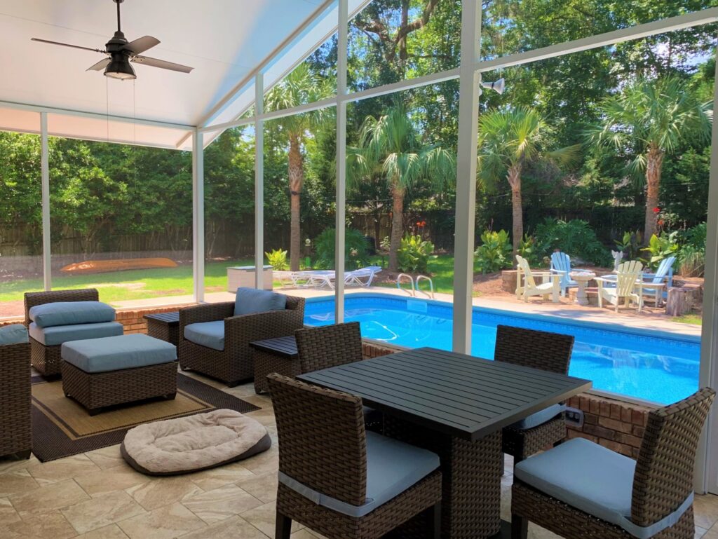 A beautifully furnished screened patio overlooking a swimming pool, built by NRG Industries in Tallahassee, FL.