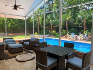 A beautifully furnished screened patio overlooking a swimming pool, built by NRG Industries in Tallahassee, FL.