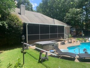 A screened-in patio next to a pool with construction materials by Four Seasons of River City in Columbus, GA.