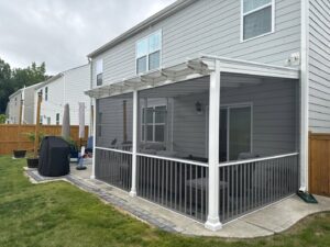 A newly built screened patio with a white frame and grey railings, furnished for outdoor living by Elite Xteriors NC in Cary, NC.