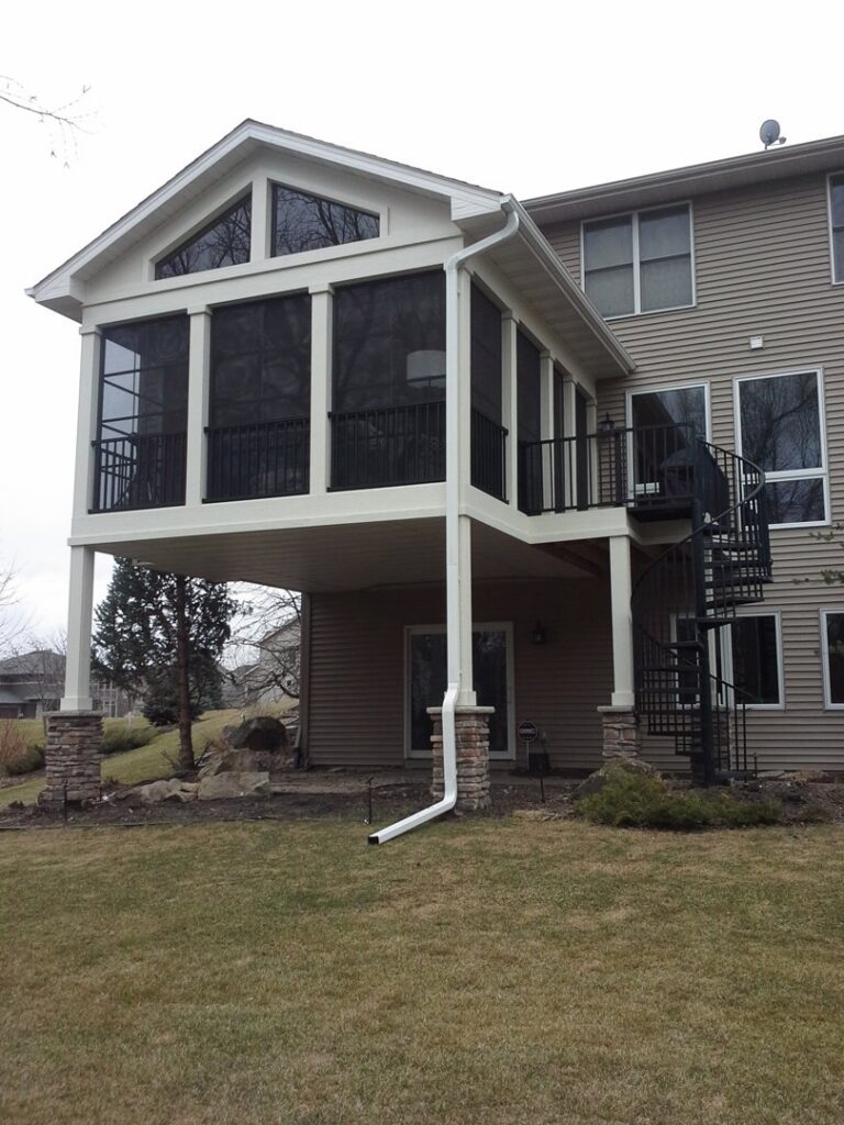 Completed screened-in porch addition with a spiral staircase on a house by Tschida Construction in Cologne, MN.