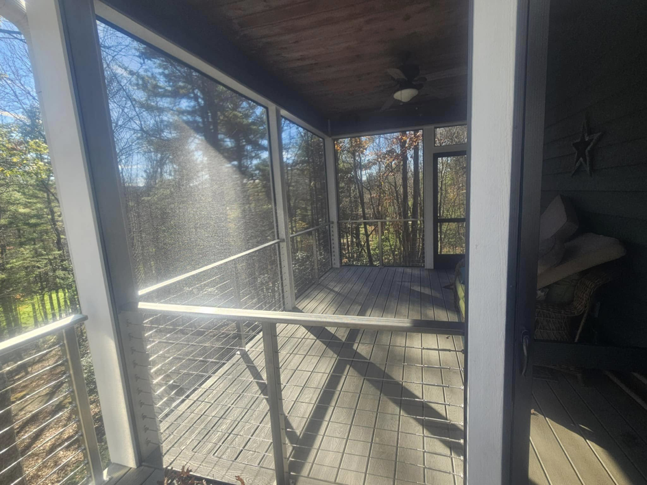 A comfortable screened porch with cable railing and a ceiling fan by American Cable & Rigging in Mills River, NC.