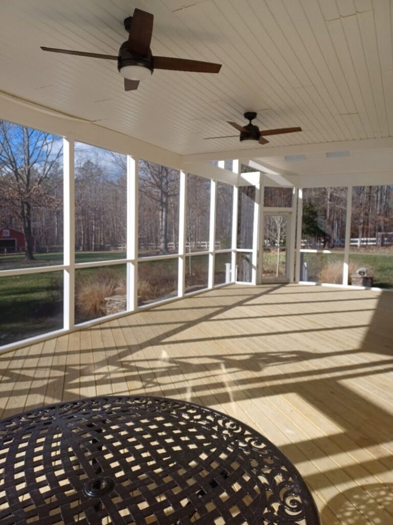 A newly installed screened-in porch with ceiling fans and a wooden deck by M&M Home Builders, LLC in Richmond, VA.