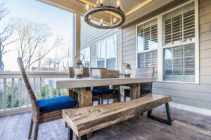 A beautifully furnished screened porch with a rustic chandelier and concrete-top table by Constructive Design Group in Raleigh, NC