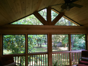 A newly constructed screened porch with wooden interior and ceiling fan by John Chatham, Construction in Atlanta, GA.