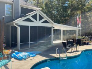 A screened-in porch and covered patio next to a swimming pool by Four Seasons of River City in Columbus, GA.