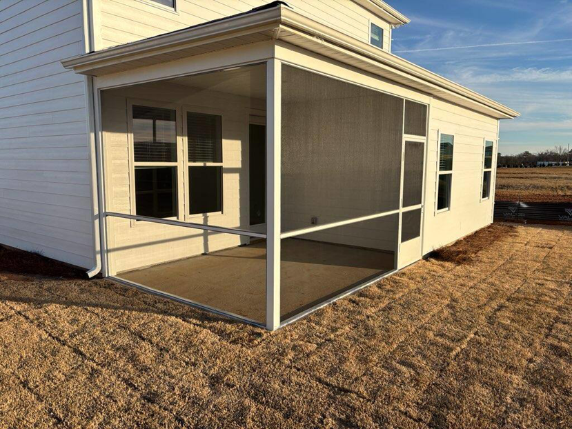 An exterior view of a newly constructed screened porch attached to a white house by AccampoBros Home Solutions in Greenville, SC.